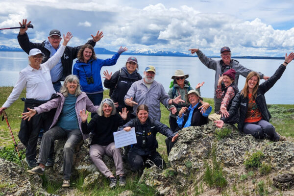 Group of happy participants posing at Yellowstone Lake in a Paul Doss geology seminar.