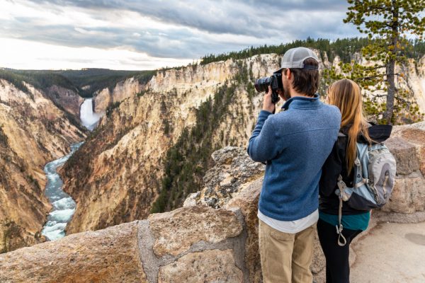 A couple taking photos of the Grand Canyon of the Yellowstone from Artist Point.